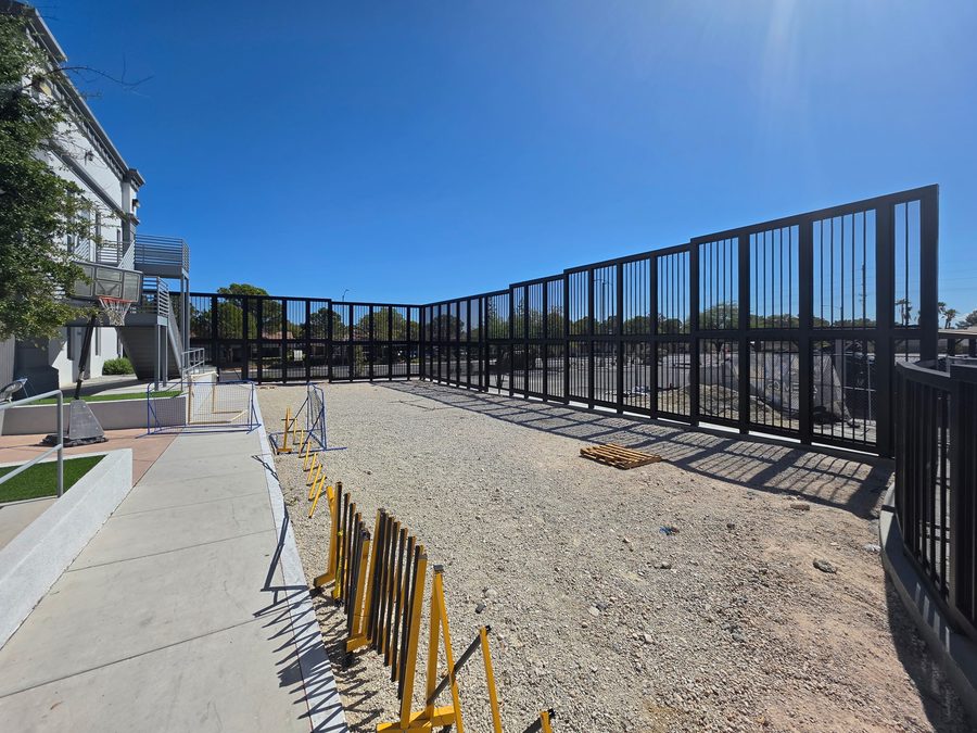 During construction: black steel picket fence going up around a gravel yard before the artificial turf, Brilliantmont, Las Vegas Valley NV