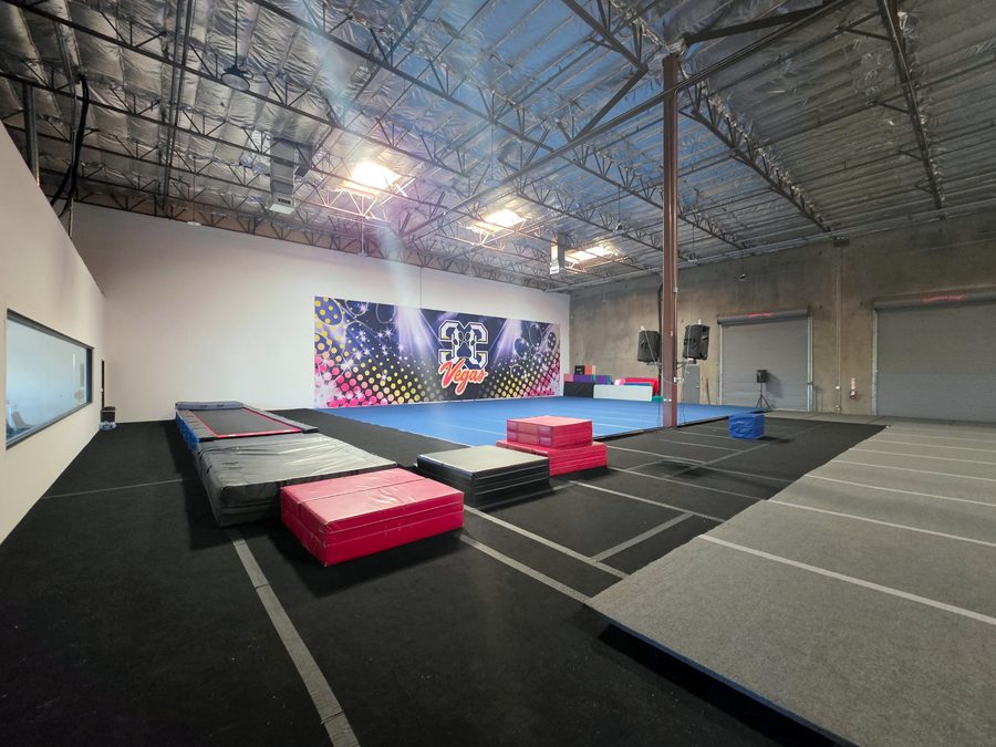 Open gym with a blue spring floor, exposed insulated roof structure and roll-up doors, CheerCats tenant improvement, Henderson NV