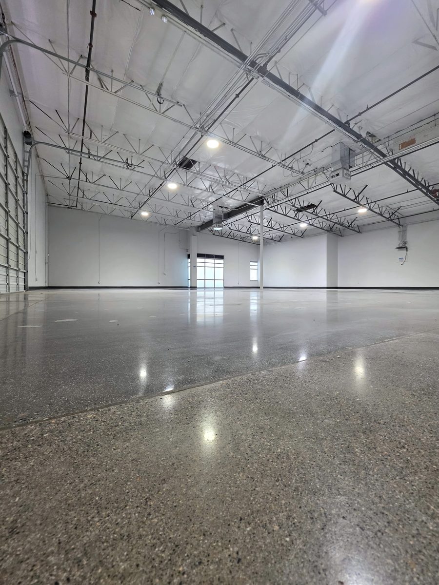 Open warehouse area with a polished concrete floor, open-web joists and roll-up doors, CheerCats project, Henderson NV