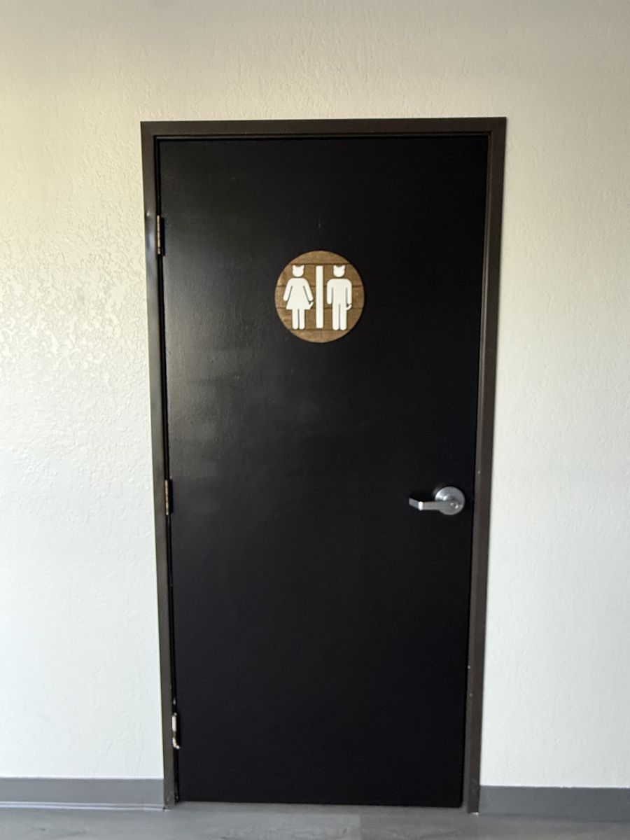 Black restroom door with round restroom sign in the finished CheerCats tenant improvement, Henderson NV